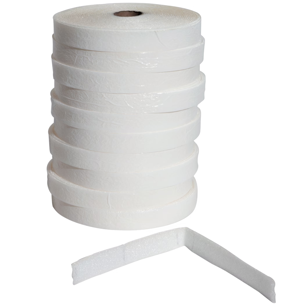 UZIN_Dummy_ES 50_5_2014-02 A vertical stack of several white adhesive foam tape rolls with textured surfaces against a white background; one foam strip lies in front bent at a right angle, revealing its thickness and porous foam texture. The rolls show a cardboard core and a slightly glossy outer layer, suitable for sealing, cushioning, weatherproofing or insulation tasks.
