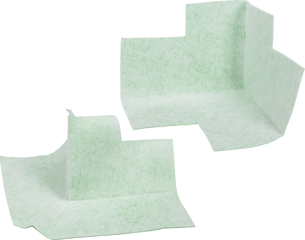 codex_Dummy_Dichteck_composing_2019-01 Two light mint-green disposable absorbent corner liners photographed against a white background. The non-woven, textured pads are preformed with a raised vertical corner and flat surrounding flanges, suggesting use as shaped underpads or protective liners for furniture, medical or hygiene applications. The material appears soft, fibrous and slightly translucent with a mottled texture; edges are irregularly cut. The liners are shown separated and oriented at different angles, highlighting the three-dimensional folded shape and the flat base areas designed to collect liquids or protect surfaces.