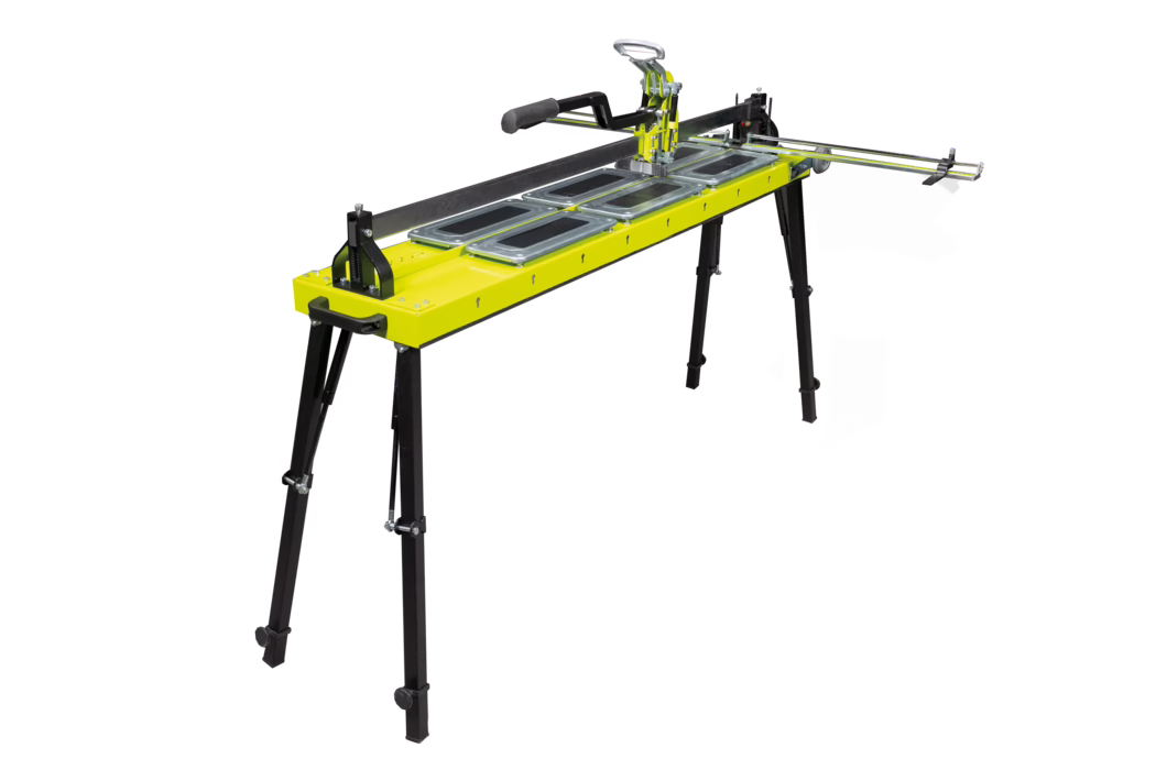 codex_Dummy_X-Cut_2024-04 Manual tile cutter mounted on a long foldable workbench with a bright green top, metal guide rails and a handheld cutting carriage, supported by adjustable black legs.